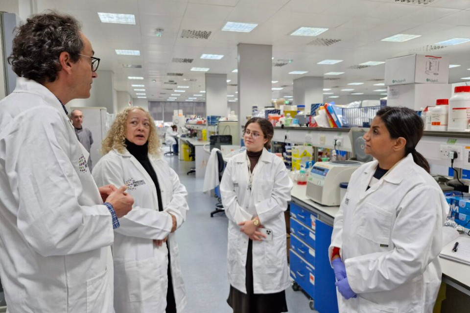 Researchers standing in lab talking with Kim Johnson, second from left
